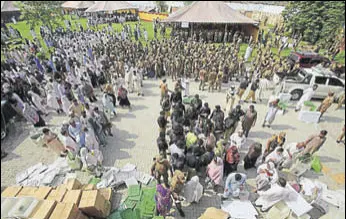  ?? AP ?? Big brother watching: Election staff receive polling material in Peshawar as soldiers look on.