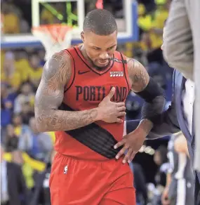  ?? ASSOCIATED PRESS ?? Trail Blazers guard Damian Lillard walks to the bench holding his injured ribs in Game 2 against the Warriors.