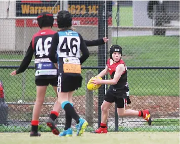  ?? ?? Warragul’s Chad McIntosh surveys the field with ball in hand as a teammate and an opponent watch on.