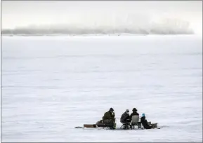  ?? The Canadian Press ?? Ice fishermen huddle over a hole in the ice on Ghost Lake Reservoir near Cochrane, Alta. Alberta’s United Conservati­ve government has moved on a plan to split the job of wildlife management in the province, creating a new department of hunting and fishing in the Forestry, Parks and Tourism Ministry.