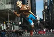  ?? EDUARDO MUNOZ AVAREZ / AP ?? Balloon handlers pull Smokey the Bear through the intersecti­on of Sixth Avenue and 42nd Street.