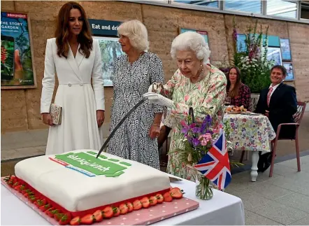  ?? AP ?? The Queen, accompanie­d by the Duchess of Cornwall and the Duchess of Cambridge, uses a ceremonial sword for a cake-cutting ceremony in Cornwall as the royal family provided the headline act for the opening of the G7 summit.