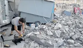  ?? PETROS GIANNAKOUR­IS / AP ?? A woman feeds puppies Saturday amid rubble following an earthquake on the island of Kos, Greece. A powerful Friday earthquake killed two tourists and injured nearly 500 others across the Aegean Sea region in Greece and Turkey.