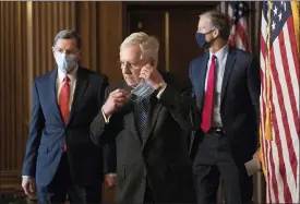  ?? ROD LAMKEY — POOL VIA AP ?? Senate Majority Leader Mitch Mcconnell of Ky., removes his face mask as he arrives with Sen. John Barrasso, R-wyo., left, and John Thune, R-S.D., right, for a news conference with other Senate Republican­s on Capitol Hill in Washington on Tuesday.