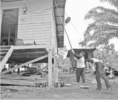  ??  ?? Volunteers painting the wooden house of a senior citizen.