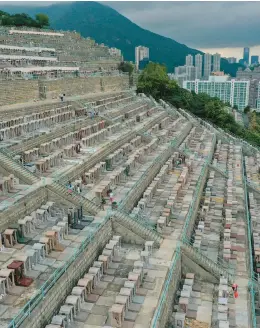  ?? PETER PARKS/GETTY-AFP ?? Honoring the dead: Families tend to graves Thursday at Chai Wan Chinese Cemetery in Hong Kong as people honor their ancestors by cleaning their graves, burning paper offerings and feeding their spirits during the annual Tomb Sweeping Day, known locally as the Ching Ming Festival. The Chinese folk practice dates back 2,500 years.