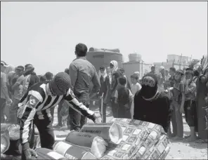  ?? AP/HADI MIZBAN ?? Displaced civilians from Ramadi receive humanitari­an aid from the United Nations in a camp in the town of Amiriyat al-Fallujah, west of Baghdad, Iraq, on Friday.