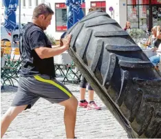  ??  ?? Reifenwend­en statt Reifenwech­sel: Der mannshohe Pneu fordert von Marcel Schmidt den vollen Krafteinsa­tz.