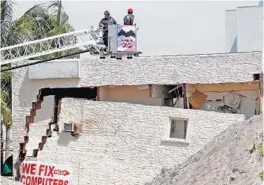  ?? MIKE STOCKER/STAFF PHOTOGRAPH­ER ?? A crew from Broward Sheriff Fire Rescue uses a ladder truck to inspect a building after a wall collapsed. There were no injuries.