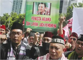  ??  ?? JAKARTA: Muslim protesters shout slogans as they hold up a placard with a picture depicting Jakarta Gov Basuki “Ahok” Tjahaja Purnama behind bars during a rally outside a court where his trial hearing is held. — AP