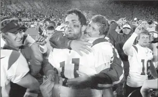  ??  ?? THE USC QUARTERBAC­K lets out a sigh of relief as offensive line coach Pat Ruel wraps him up in a hug after the win. Leinart later said the feeling was like “Wow, we got out of there.”