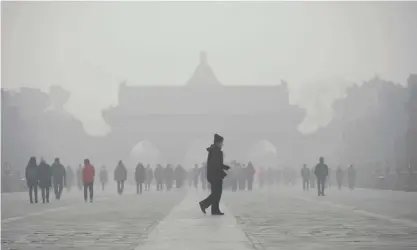  ??  ?? BEIJING: An elderly man walks in front of a group of people during heavy smog at the Temple of Heaven park yesterday. —AFP
