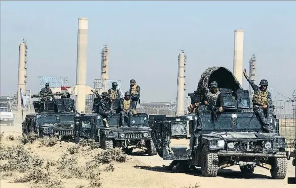  ?? AHMAD AL-RUBAYE / AFP ?? Soldados del ejército iraquí pasan por delante de una planta petrolífer­a en dirección a la ciudad de Kirkuk