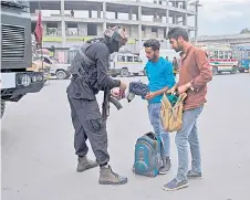  ?? — AFP photo ?? A Special Operations Group (SOG) personnel checks a bag of a man along a street on the eve of the second anniversar­y of the abrogation of the Article 370, in Srinagar.