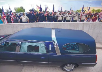  ?? ADOLPHE PIERRE-LOUIS/JOURNAL ?? Officers salute the hearse carrying Hatch police officer Jose Chavez while it backs up a ramp at the Pan American Center in Las Cruces on Sunday. Chavez was killed Aug. 12 while conducting a traffic stop.