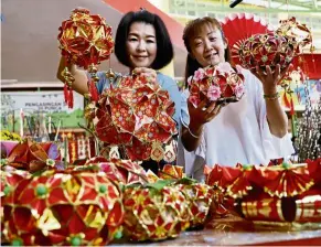  ??  ?? Delightful: Lim and her cousin Lim Chin Sien (left) showing the the lanterns Lim made at her stall at the tanjung Bungah market, Penang.