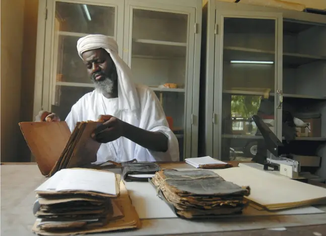  ?? CANDACE FEIT / NEW YORK TIMES FILES ?? Alkamis Cisse works to restore ancient manuscript­s at the Ahmed Baba institute, a government-run library in Timbuktu in 2007. The city is home to more
than 100,000 such artifacts, and experts are concerned the arrival of the Mali rebellion’s competing...
