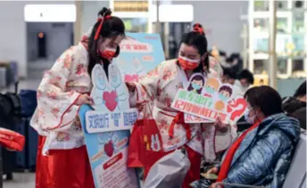  ?? ?? Volunteers in hanfu distribute COVID-19 prevention kits to passengers at a railway station in Xuzhou, Jiangsu Province, on January 21, 2021