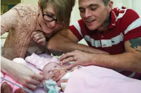  ?? AP PHOTO ?? Naomi Findlay and Dean Wilkins look at their daughter, three-week-old Vanellope Hope Wilkins who was born with a rare condition in which the heart grows on the outside of the body, at Glenfield Hospital in Leicester, England on Monday. To see video...