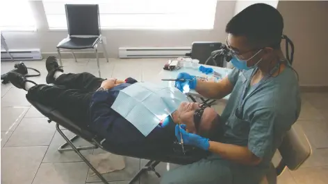  ?? JASON PAYNE ?? UBC School of Dentistry dental hygiene student Timothy Supan treats Dwight Harvey during a free dental clinic in Surrey last week.