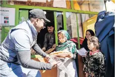  ?? ?? CHILDREN in Afghanista­n receive bread from Ama’s Bakery of Hope.