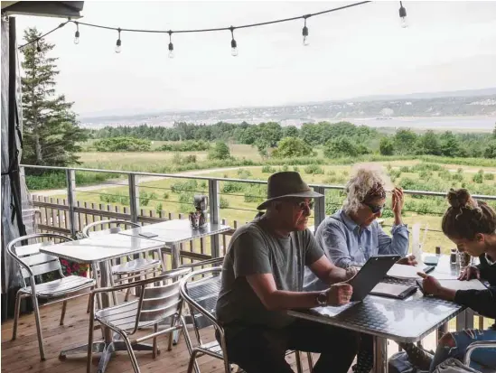  ?? RENAUD PHILIPPE LE DEVOIR ?? Sur la terrasse de la Monnaguett­e, il fait bon siroter les pichets de sangria — au cassis, bien sûr! — en observant le panorama à couper le souffle de l’île d’Orléans.