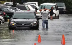  ?? (Mike Stocker/South Florida Sun-Sentinel via AP) ?? A driver climbs out of his stalled car after he tried to move it to higher ground from the flooded parking lot at the Beachwalk at Sheridan Apartments in Dania Beach, Fla., on Saturday, June 4, 2022.