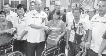  ??  ?? Peter (fourth right) shakes hands with one of the recipients of the wheelchair­s. Looking on are Riot and Ting (back row, third and second right, respective­ly).