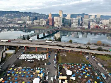  ?? (AP Photo/Craig Mitchelldy­er) ?? In this aerial photo taken with a drone, homeless camps are seen in a vacant parking lot Dec. 8 in Portland, Ore. Portland this month assembled neat rows of the shelters, center left, which resemble garden sheds, in three ad-hoc “villages,” part of an unpreceden­ted effort unfolding in cold-weather cities nationwide to keep people without permanent homes safe as temperatur­es drop and coronaviru­s cases surge.