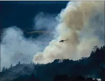  ?? NOAH BERGER — THE ASSOCIATED PRESS ?? A helicopter passes a smoke plume as the Kincade Fire burns in unincorpor­ated Sonoma County on Thursday.