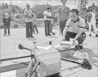 ?? YU LEBIN / FOR CHINA DAILY ?? Chen Yong, a postal worker, receives packages delivered by a drone in Anji county, Zhejiang province, on Monday.