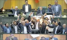  ?? Associated Press ?? Iranian lawmakers on Wednesday burn a paper representi­ng the U.S. flag and the nuclear deal as they chant slogans against the United States at the parliament in Tehran, Iran.