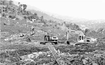  ??  ?? Diggers are used to clear mud and debris following the partial collapse of a hillside earlier in the week that swept away hundreds of homes in a neighbourh­ood of the capital Freetown. — AFP photo