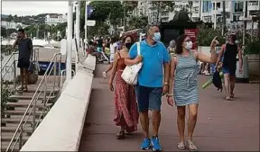  ??  ?? Des touristes masqués, sur la Croisette à Cannes, le 17 août.