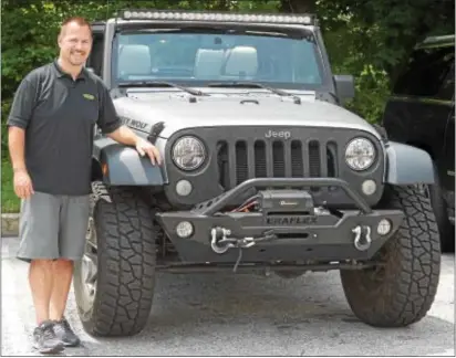  ?? PETE BANNAN DIGITAL FIRST MEDIA ?? John Stewart, president of Quadratec, is shown at the company’s headquarte­rs in West Goshen with a 2014 Jeep Wrangler.