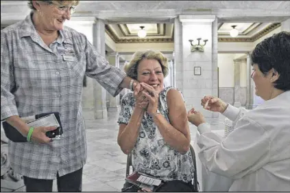  ?? LAURIE SKRIVAN / AP ?? Carol Evans (left) offers a comforting hand to co-worker Dusty Reese as nurse Kandie Halleran administer­s Reese a flu shot in the main lobby rotunda area of City Hall on Oct. 24 in St. Louis.