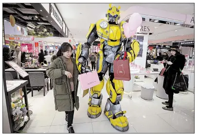 ?? AP ?? A person dressed as the Transforme­rs action figure Bumblebee helps a woman carry bags last week at a shopping mall in Handan, China. U.S. and Chinese officials resumed trade talks Tuesday in Washington.