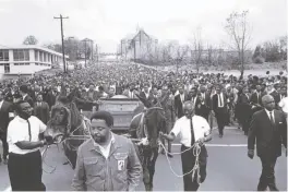  ?? Bob Adelman 1968 ?? Above: Bob Adelman examines photos from the civil rights movement. Left: In an April 1968 photo by Adelman, the body of Martin Luther King Jr. is carried to Atlanta’s Morehouse College on a mule- drawn wagon, his aides dressed in denim. The wagon,...