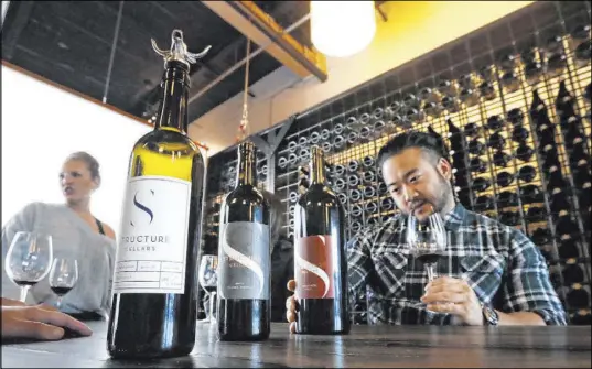  ?? Elaine Thompson The Associated Press ?? Mike Roh sniffs wine at the Structure Cellars tasting room in Seattle. From less than 20 wineries in 1981, the Washington wine industry has grown to more than 1,000. The state is the second-largest producer of premium wines in the U.S., trailing California.