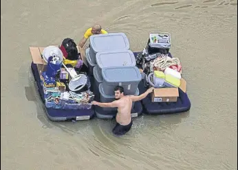  ?? REUTERS ?? Residents wade through flood waters with their belongings in Houston on Wednesday.