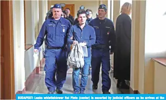  ??  ?? BUDAPEST: Leaks whistleblo­wer Rui Pinto (center) is escorted by judicial officers as he arrives at the Metropolit­an Court in Budapest, Hungary, for his trial. — AFP