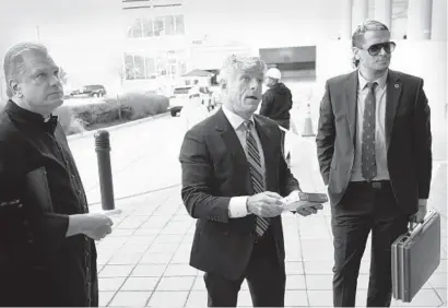  ?? GAIL BURTON/AP ?? Father Paul Kalchik, left, St. Michael’s Media founder and CEO Michael Voris, center, and Milo Yiannopoul­os talk with a court officer Sept. 30 outside the federal courthouse in Baltimore. St. Michael’s Media is planning a rally at MECU Pavilion next month.