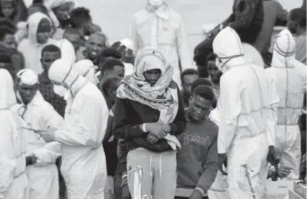  ?? Photos by Salvatore Cavalli, The Associated Press ?? Migrants wait to disembark the Italian Coast Guard vessel Diciotti on Wednesday as it docks in Sicily.