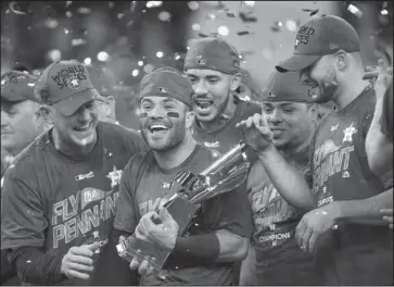  ?? The Associated Press ?? AMERICAN LEAGUE CHAMPIONS: Houston Astros’ Jose Altuve holds up the championsh­ip trophy after winning Game 7 of the American League Championsh­ip Series against the New York Yankees Saturday in Houston. The Astros won 4-0 to win the series.