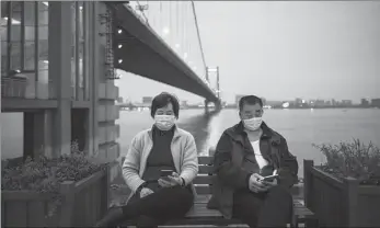  ?? ZHONG RUIJUN / FOR CHINA DAILY ?? A couple pass time with their cellphones at a park in Wuhan, Hubei province, on April 1. Local residents began to resume outdoor activities as the COVID-19 situation improved.