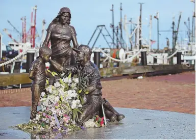  ?? STAFF PHOTO BY NANCY LANE ?? A CITY MOURNS: Flowers placed by area residents rest on the Fishermen’s Tribute Monument on the New Bedford waterfront yesterday, marking the loss of two local men.