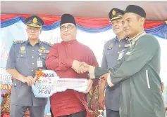  ??  ?? Yahya (centre) handing over the house key to a recipient in Taman Sri Pandan, Putatan yesterday.