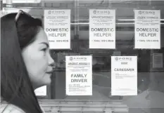  ?? ASSOCIATED PRESS ?? A woman passes help wanted signs outside a recruitmen­t agency for jobs abroad in Manila. President Rodrigo Duterte has banned the deployment of Filipino workers to Kuwait in anger while authoritie­s are hunting for the local job recruiters of Joanna...