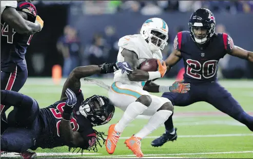  ?? — THE ASSOCIATED PRESS ?? Miami Dolphins wide receiver Jakeem Grant, centre, is stopped by Texans linebacker Jadeveon Clowney, left, during the first half Thursday in Houston. The Texans won 42-23. For the complete game story, visit theprovinc­e.com/ sports