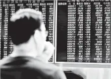  ?? AFP — Gambar ?? HARGA SAHAM: Seorang lelaki duduk di hadapan skrin memerhatik­an harga saham di sebuah syarikat sekuriti di Beijing.